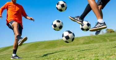 Soccer player juggling a ball on a grassy field.