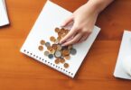 Person counting coins with notebook and coffee in Australia.
