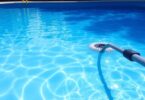 Pool vacuuming equipment in a sparkling blue pool.