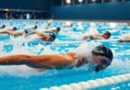 Swimmers racing in a sparkling blue pool.