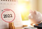 Calendar date circled, coins, piggy bank, calculator, sunlight.