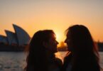 Couple embracing against Sydney Opera House backdrop.