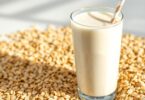 Glass of oat milk with oats and a straw.