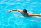 Adult swimmer powering through clear blue water.