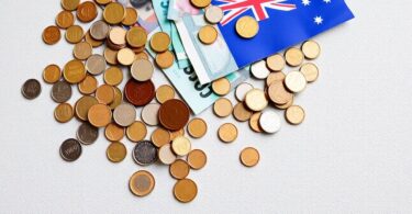 Australian coins and banknotes scattered on a map of Australia.