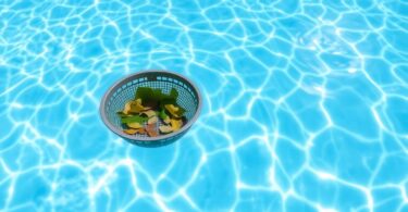 Pool skimmer collecting leaves from clear water surface.