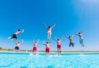 People diving into a bright blue swimming pool in Australia.