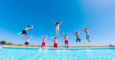 People diving into a bright blue swimming pool in Australia.