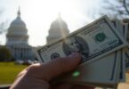 Hand holding money with Capitol building background