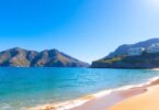 Tranquil Sydney beach with cliffs and modern buildings.
