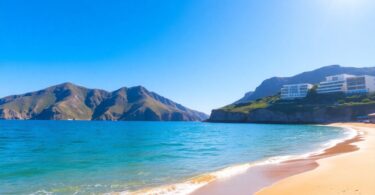 Tranquil Sydney beach with cliffs and modern buildings.