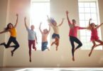 Young dancers leaping joyfully in a sunlit studio.