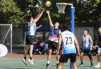 Netball players competing on a sunny outdoor court.