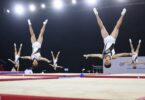 Elite gymnasts performing aerial acrobatics in a training facility.