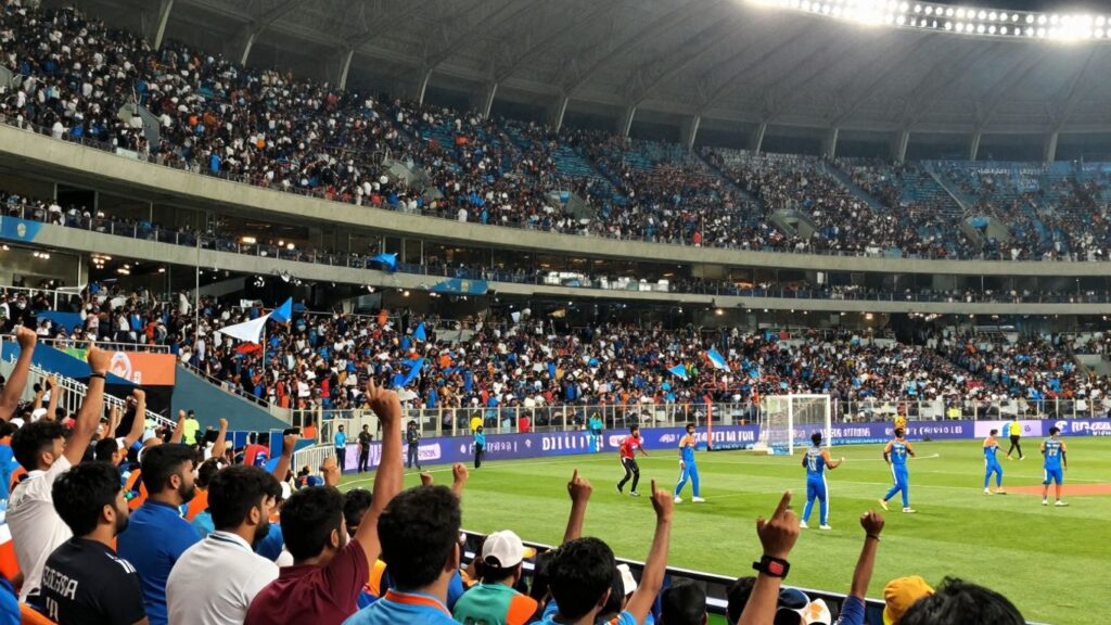 Indian sports fans cheering in a brightly lit stadium.