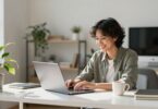 Person working on laptop at home desk.