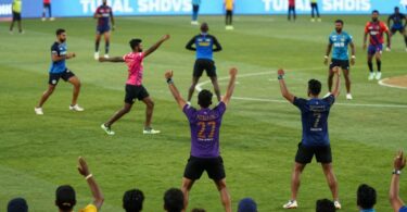 Indian sports fans cheering in a brightly lit stadium.