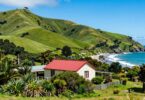 New Zealand landscape with hills, coast, and cottage.