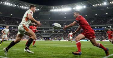 Rugby players in action on a green pitch.