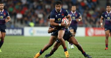 Rugby league players in a fierce tackle on a grass field.
