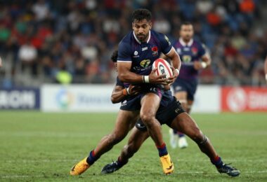 Rugby league players in a fierce tackle on a grass field.