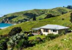 New Zealand landscape with hills, coast, and house.