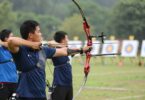 Archers aiming bows at distant targets in a natural setting.