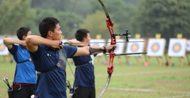Archers aiming bows at distant targets in a natural setting.