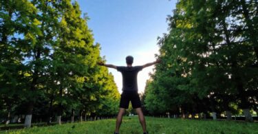 Person stretching outdoors at sunrise, embracing wellness.