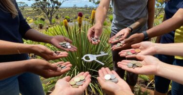 People reaching for coins and key in WA landscape.