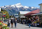 New Zealand street with shops, people, and mountains.