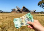 Australian dollars in hand with iconic landmarks.