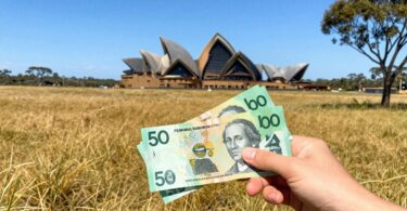 Australian dollars in hand with iconic landmarks.