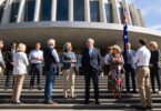 Australians outside a government building with flag and sunlight