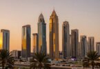 Dubai skyline at sunset with skyscrapers and palm trees.