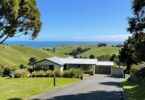 Modern house on green hills overlooking New Zealand coast.