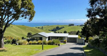 Modern house on green hills overlooking New Zealand coast.