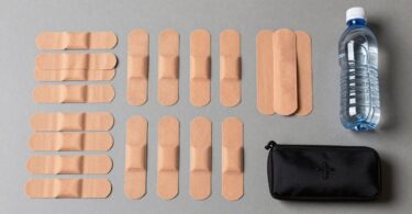 Sports trainer kit with tape, bandages, and water bottle.