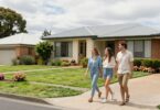 Couple walking towards dream home on sunny street.